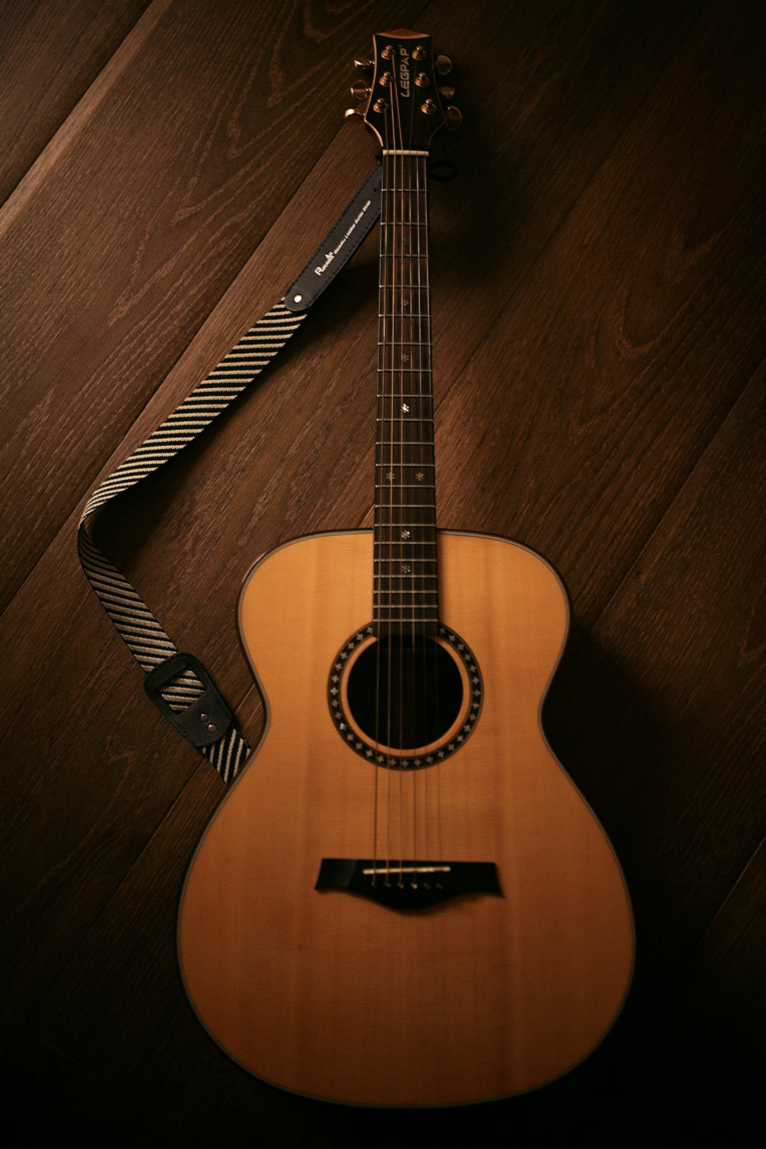 brown acoustic guitar on brown wooden floor
