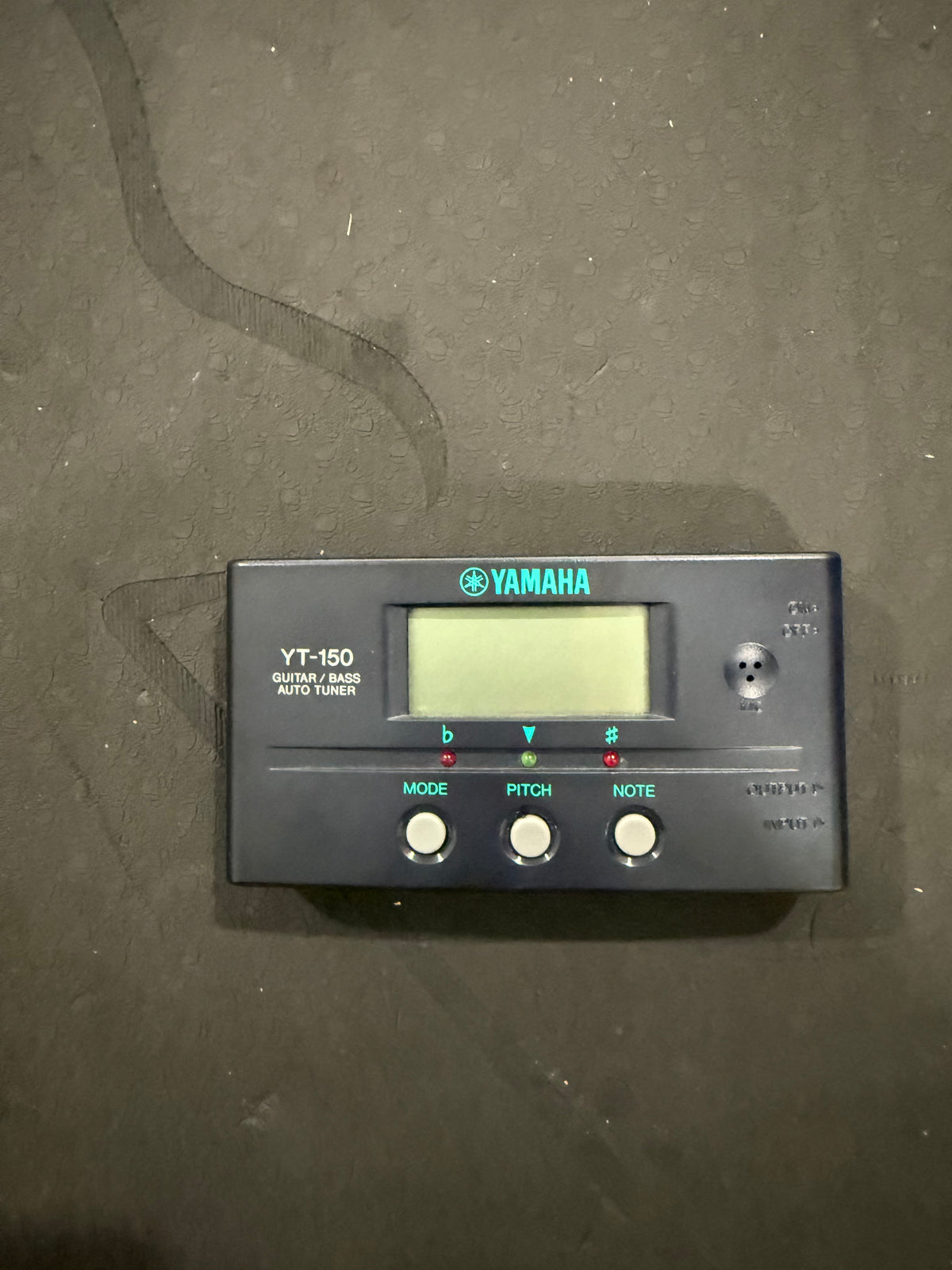 Yamaha YT150 guitar and bass auto tuner device, compact black tuner with digital display for precise instrument tuning.
