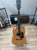 Used Washburn HD10S Heritage acoustic guitar with a natural wood finish and classic shape displayed on a soft surface.